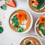 Overhead of 4 bowls of strawberry watermelon gazpacho on a pink background