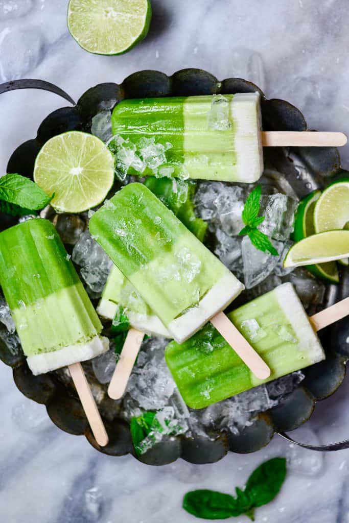 Overhead of green popsicles on a circular tray full of ice