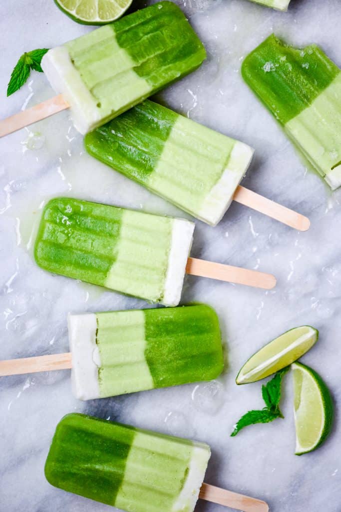 Overhead of green popsicles on a marble background with crushed ice