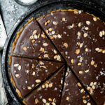 Overhead of chocolate ganache pretzel tart on a cooling rack with dark, moody background