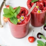 Close up of cherry watermelon slushie garnished with mint on a white serving tray