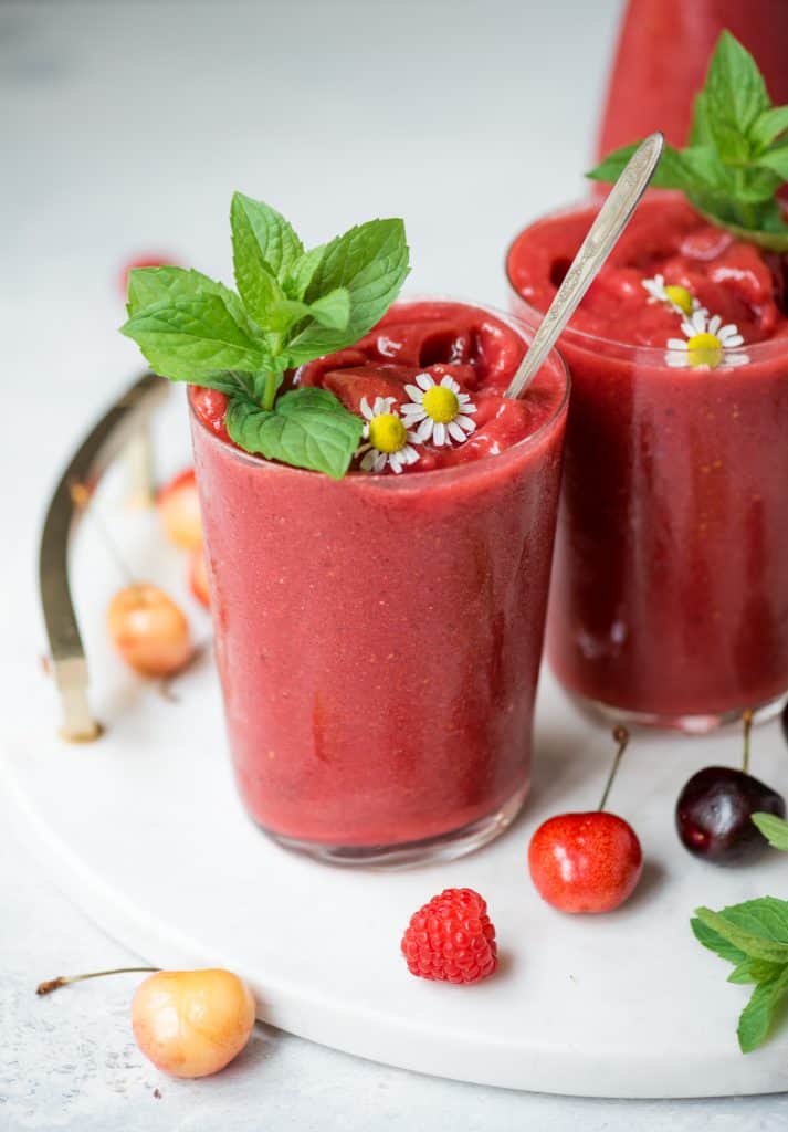 Side view of cherry watermelon slushie garnished with mint on a white serving tray