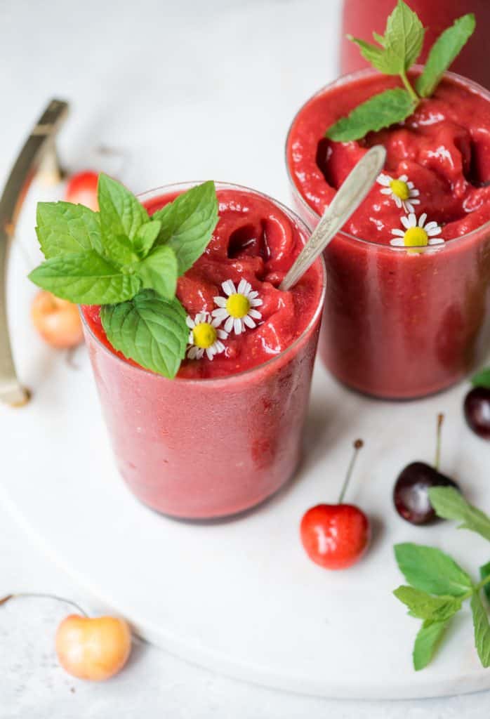 Close up of cherry watermelon slushie garnished with mint on a white serving tray