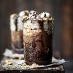Side view of s'mores overnight oats drizzled with chocolate and marshmallows on a rustic wood board