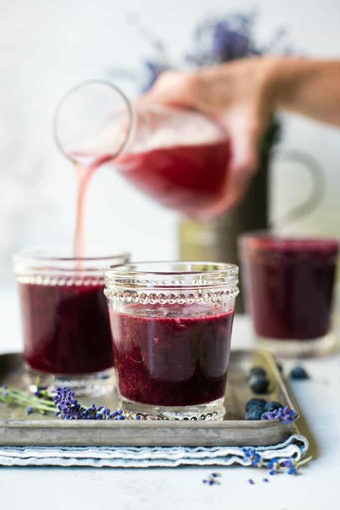Pouring blueberry lavender margaritas into small glasses