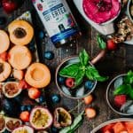 Overhead of fresh summer fruit board and berry moscow mules with fresh basil styled on a rustic wood background