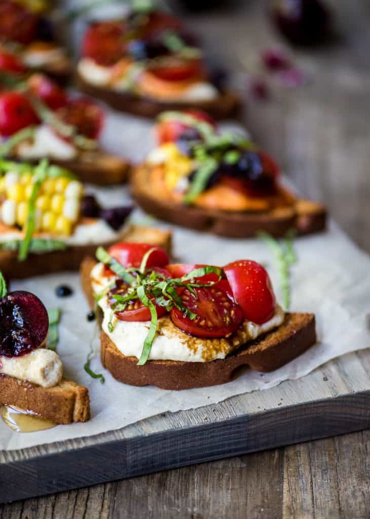 Side view of crostini topped with tomatoes, basil and vegan ricotta