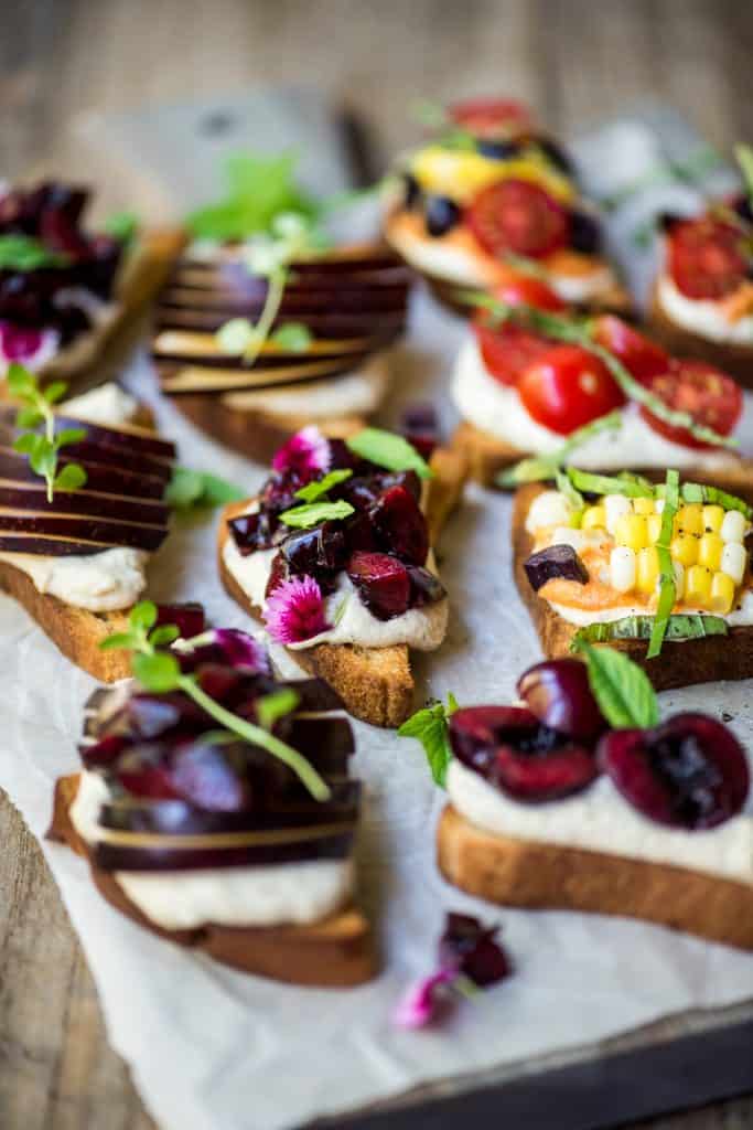 Side angle of crostini topped with cherries, ricotta and herbs