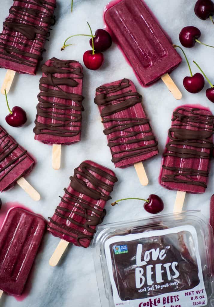 Overhead of cherry popsicles drizzled with dark chocolate on a marble background