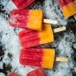 Watermelon Peach Prosecco Popsicles on a sheet pan filled with crushed ice