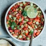 Bowl of strawberry avocado salsa in a white bowl garnished with lime