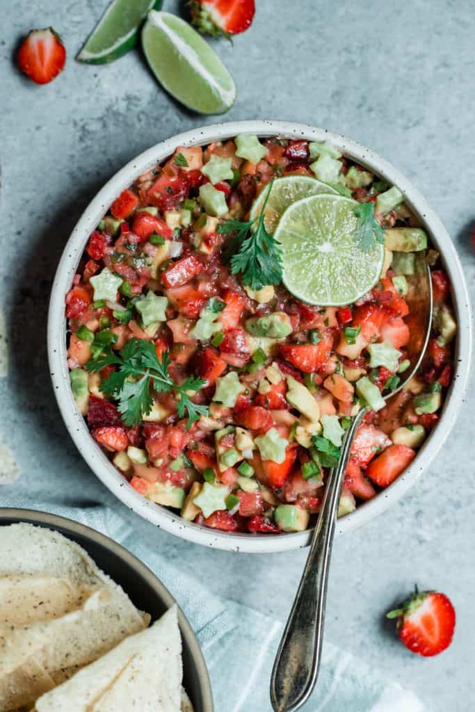 Bowl of strawberry avocado salsa in a white bowl garnished with lime