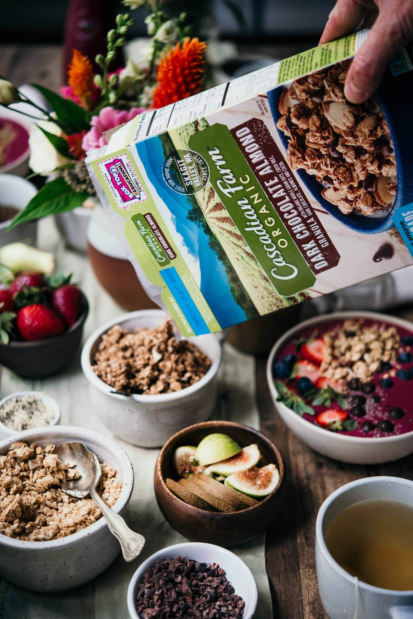 Pouring Cascadian farm granola into a small white bowl on a table