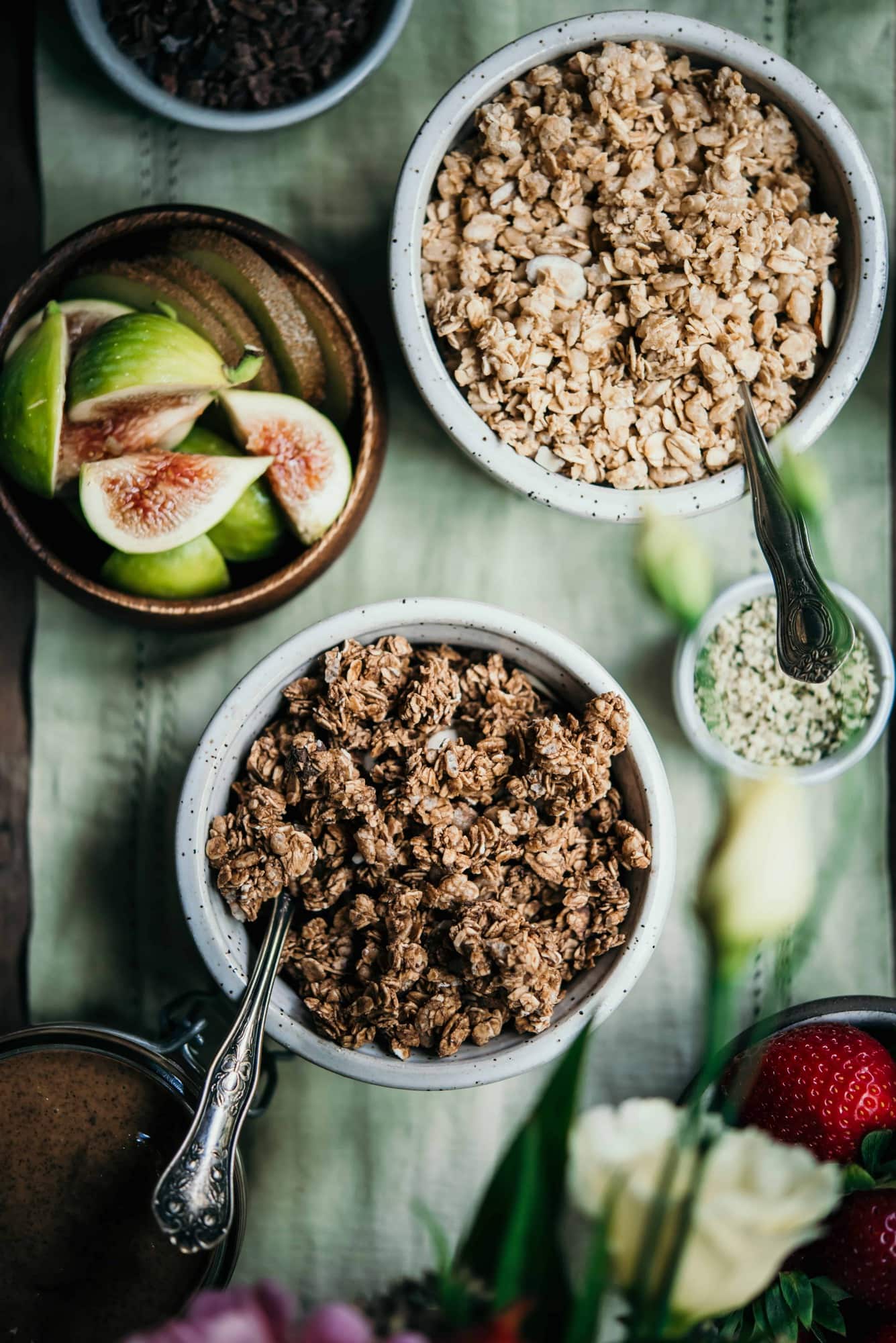 Two small white bowls of granola on a light green tablecloth