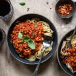 Overhead of zucchini noodles with a vegan bolognese sauce and fresh tomatoes in a large gray bowl on a wood surface