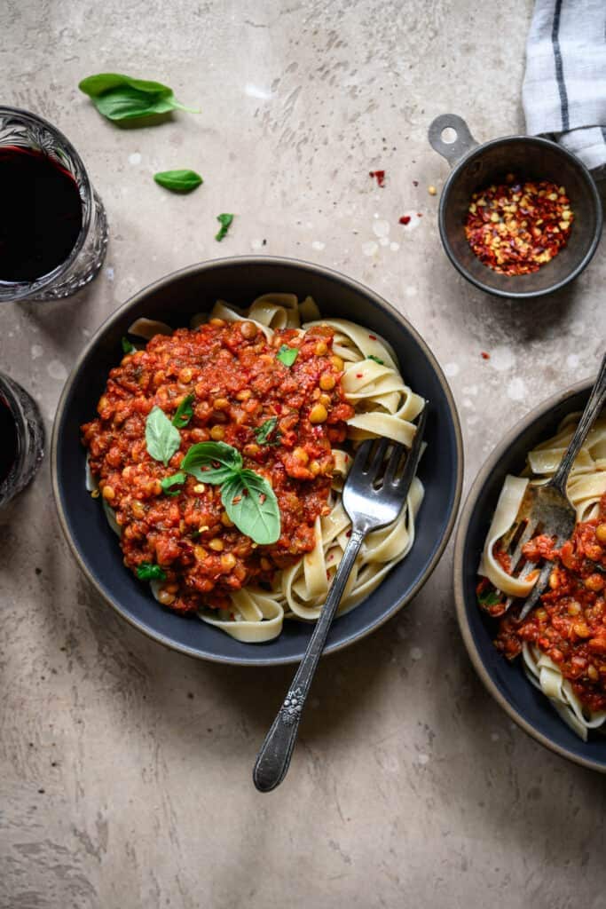 Overhead view of vegan lentil bolognese over pasta in two bowls