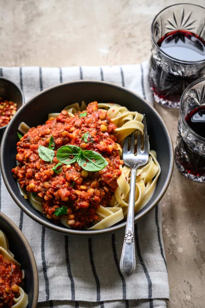 Side view of vegan bolognese served over fettuccine with fresh basil