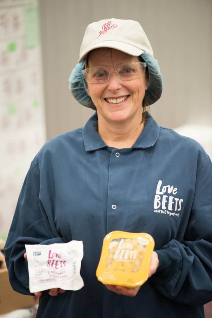 Beth holding up Love Beets packaged ready-to-eat beets at their factory