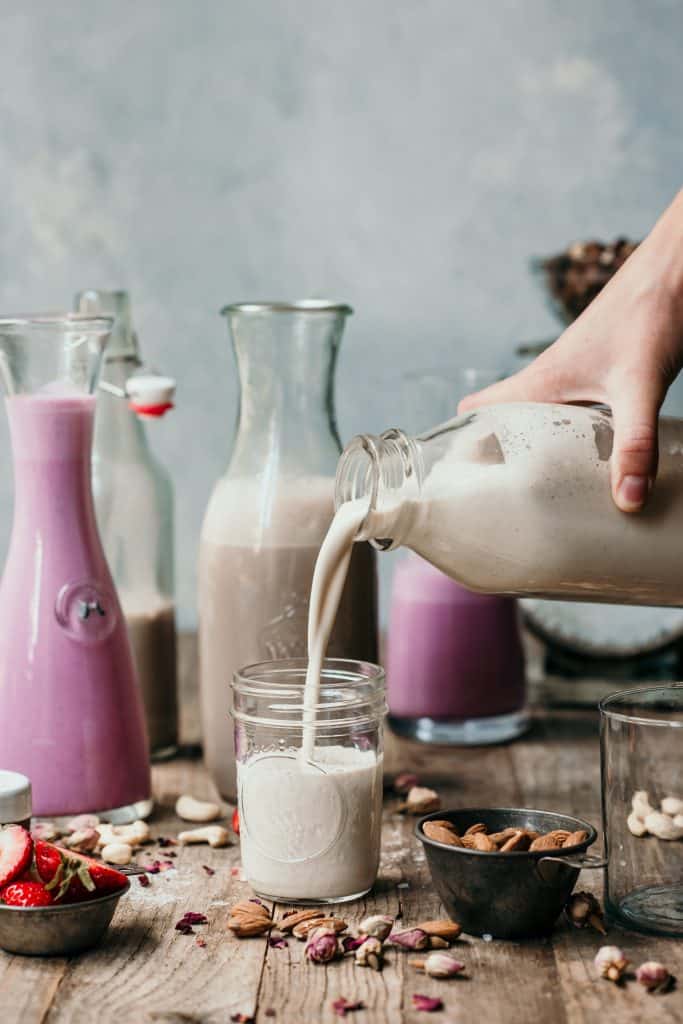 Pouring homemade vanilla almond milk into a glass jar