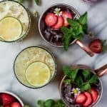Overhead of pineapple jalapeño margaritas and strawberry moscow mules on a marble background