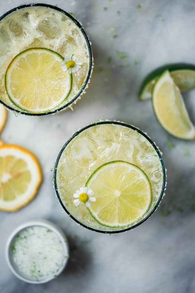 Close up overhead of pineapple jalapeño margarita garnished with lime on a marble background