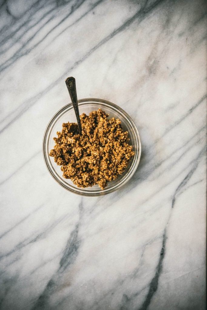 Crunchy chickpea salted caramel tart crust in a bowl on marble surface