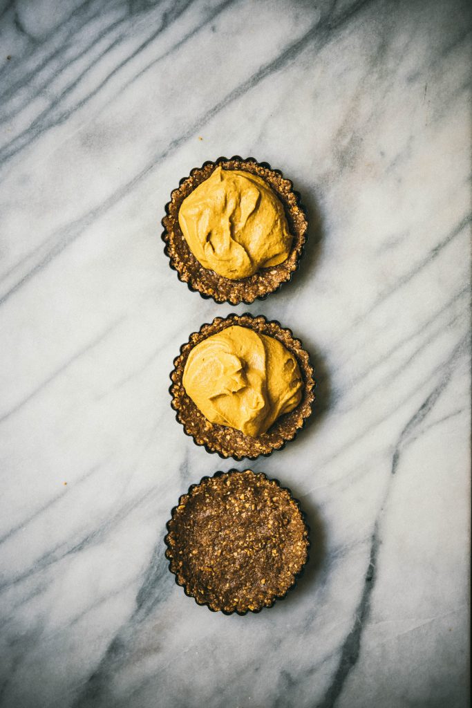 3 mini pumpkin cheesecake tarts on marble surface