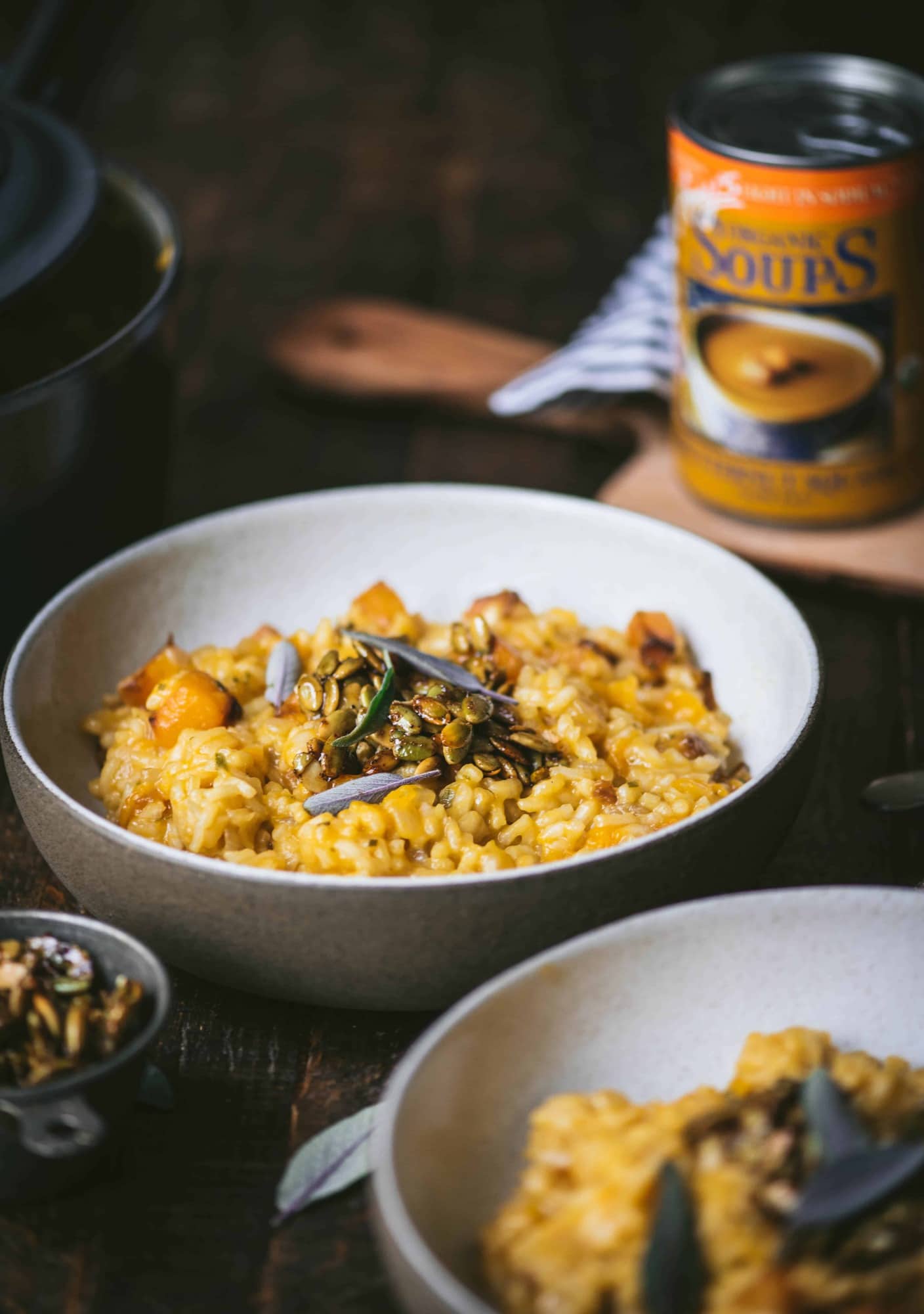 Side view of two bowls of butternut squash risotto with fresh sage. On a rustic wood background