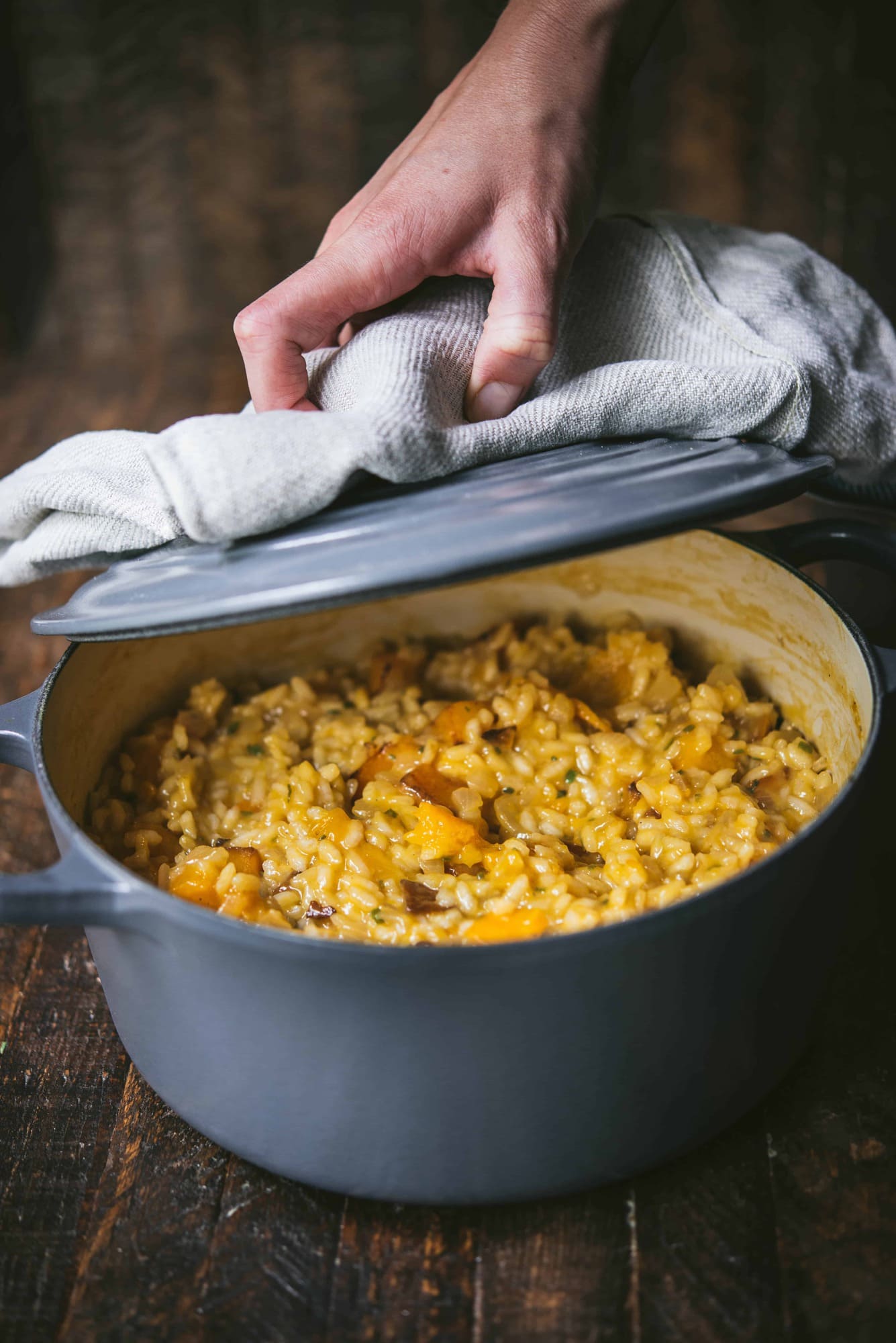 Hand opening pot of butternut squash risotto