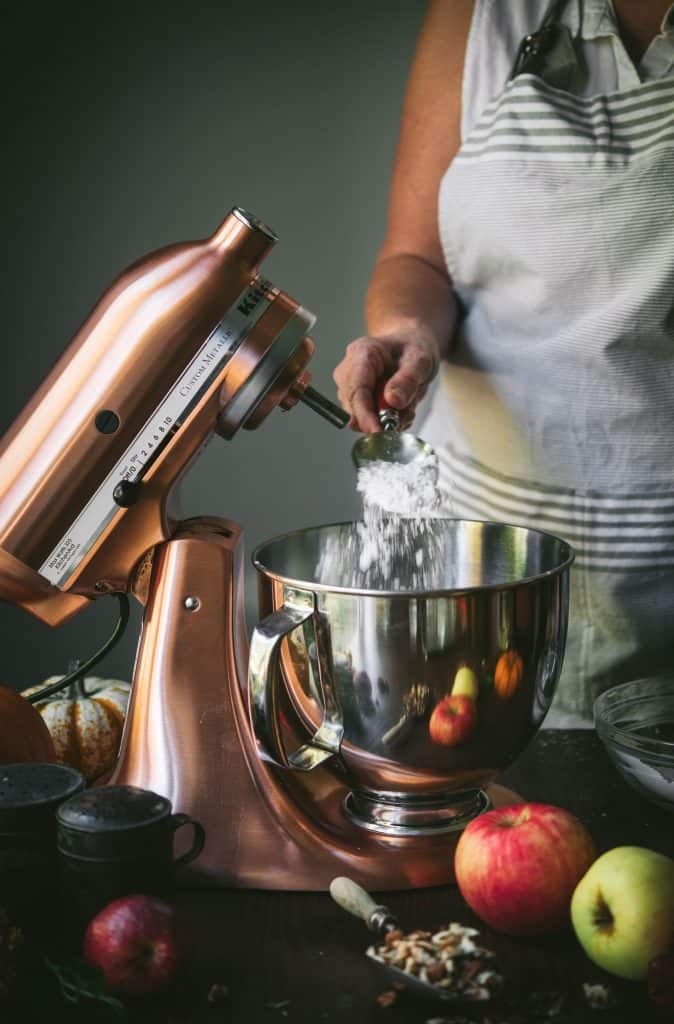 Action shot of pouring flour into a copper stand mixer