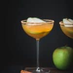 Apple cider pear martini in a long-stemmed coupe glass with dark moody background