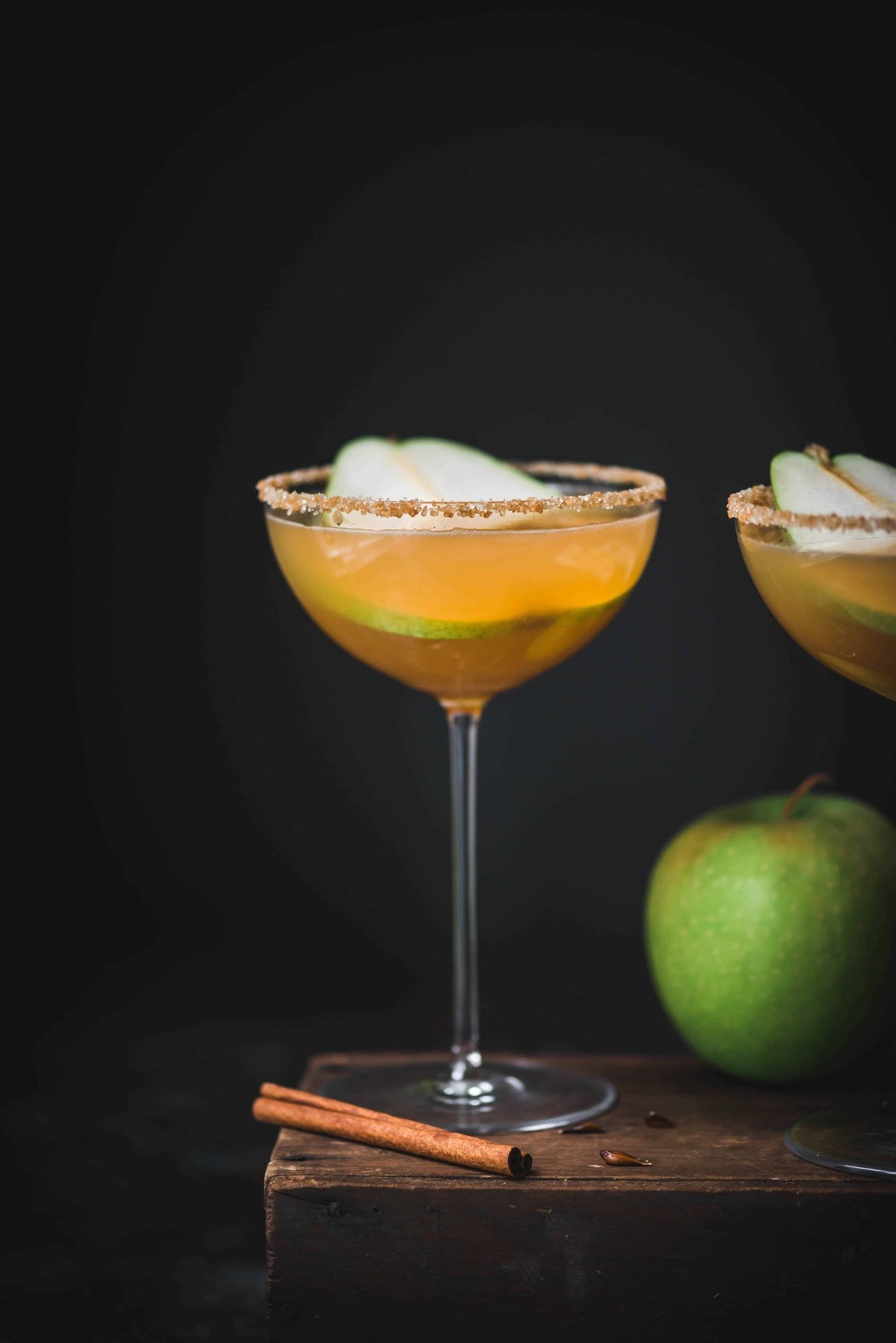 Apple cider pear martini in a long-stemmed coupe glass with dark moody background