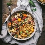 Bowl of bowtie mediterranean pasta with charred lemons on rustic background with fresh herbs