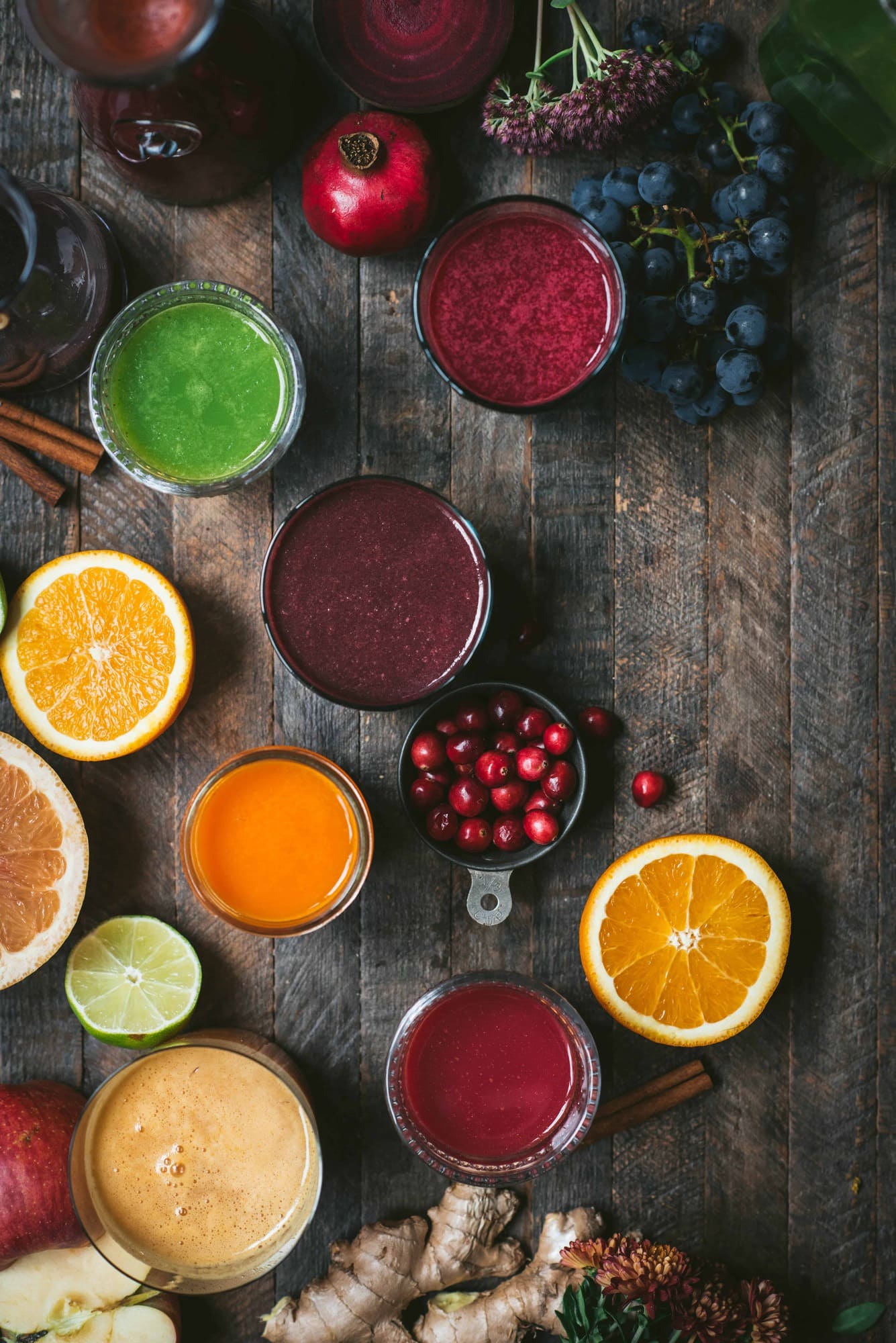 Overhead of colorful fresh glasses of juice and fresh fruit on a rustic wood background