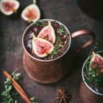 Side view of fig moscow mule in copper mug with cinnamon sticks and fresh thyme