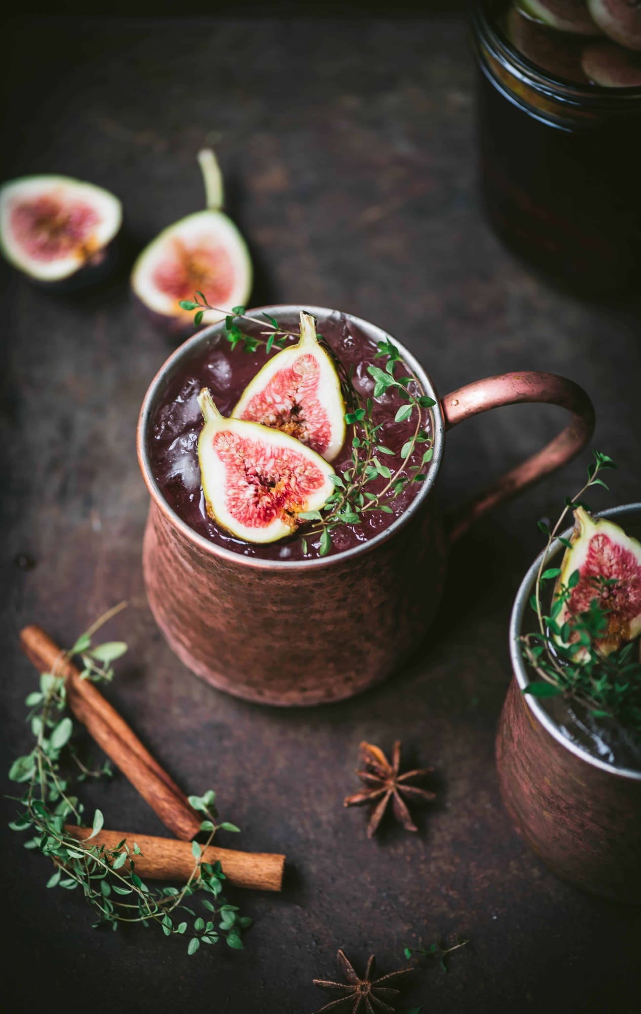 Side view of fig moscow mule in copper mug with cinnamon sticks and fresh thyme