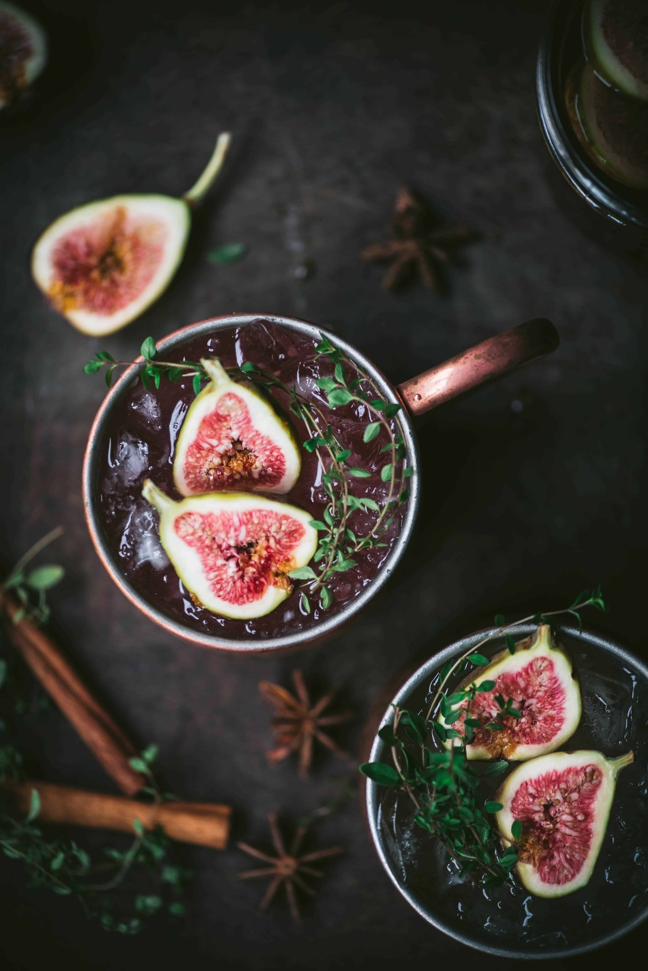 Overhead view of fig moscow mule in copper mug with cinnamon sticks and fresh thyme