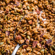 close up view of pumpkin spice granola on a large serving spoon on sheet pan.