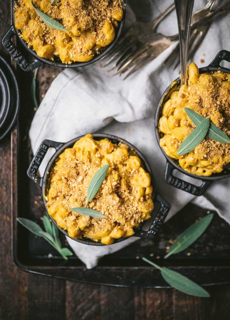 Overhead of vegan pumpkin mac and cheese in 3 mini Staub black cast iron coquettes
