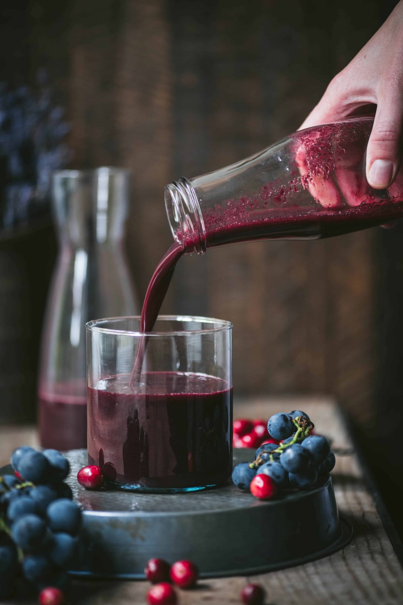 Homemade concord grape and cranberry juice being poured into a glass