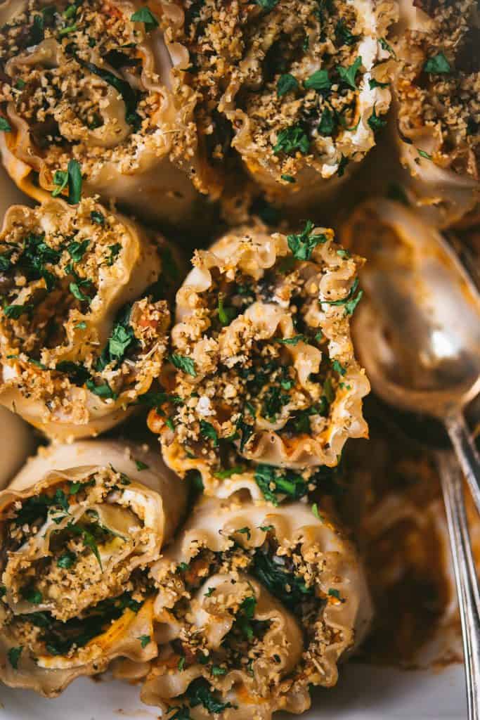 Close up of vegan butternut squash lasagna roll ups with two spoons