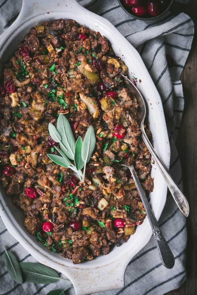 Close up of gluten free stuffing with fresh sage in an oval baking pan with two spoons