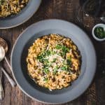 Overhead of wild mushroom risotto in gray bowl served with red wine