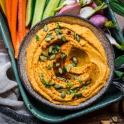 Overhead view of pumpkin hummus in a bowl garnished with pumpkin seeds.