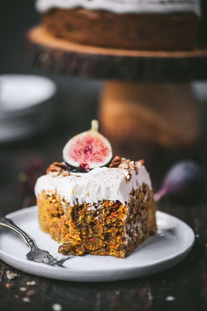 Close up of piece of carrot cake with bite taken out on a white plate