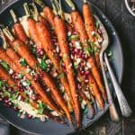 Close up of harissa roasted carrots over pumpkin hummus on a gray plate
