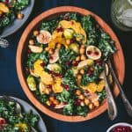 Large bowl of kale salad with fall roasted vegetables, tahini dressing and a bowl of pomegranate seeds