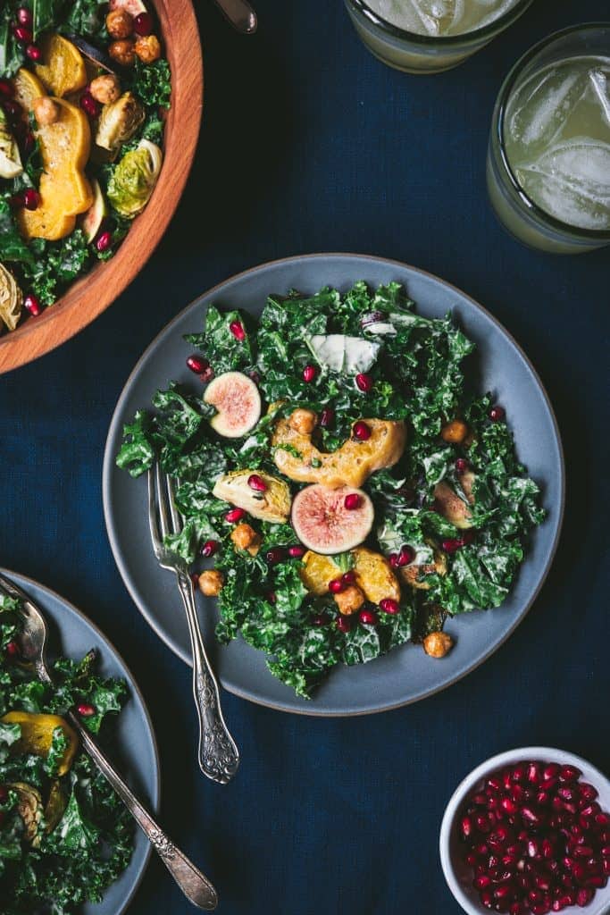 Overhead of kale salad with roasted vegetables and tahini dressing on a gray plate