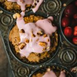 Close up overhead of cranberry apple muffins with pink cranberry glaze in an antique muffin tray