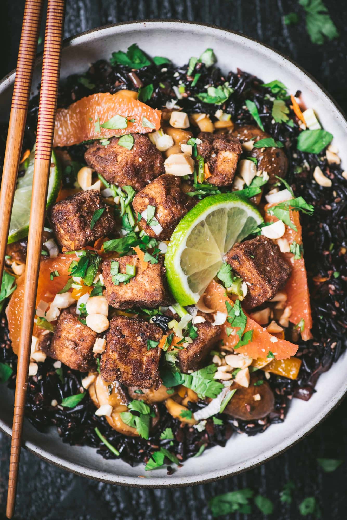 Close up of black rice with veggies and five spice tofu in a bowl with chopsticks